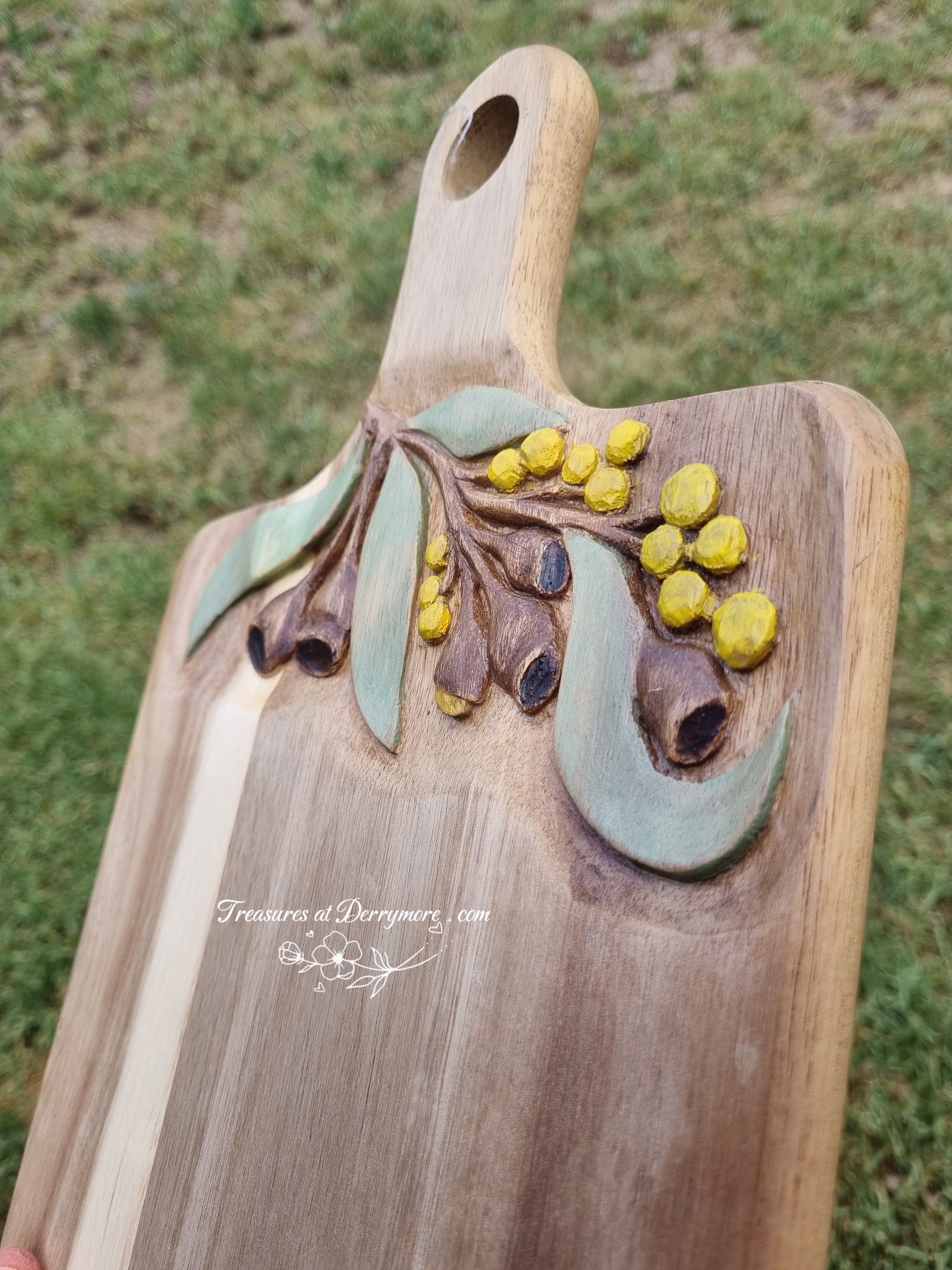 Chopping board with Australian themed design hand carved on upper part of board. Wattle, Eucalyptus leaves, gum nuts