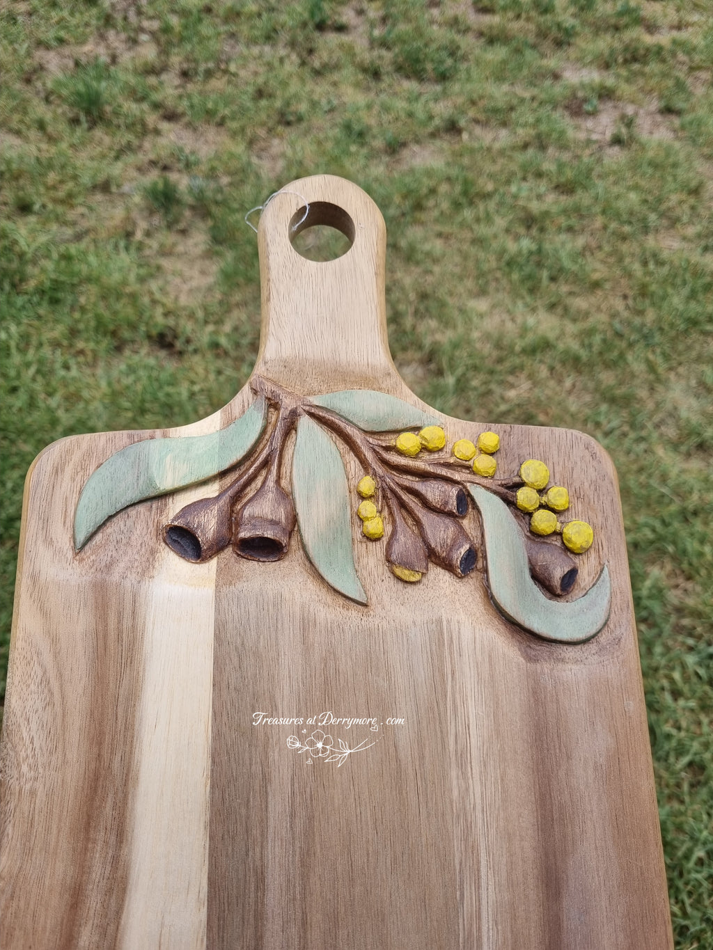 Chopping board with Australian themed design hand carved on upper part of board. Relief carved Wattle, Eucalyptus leaves, gum nuts