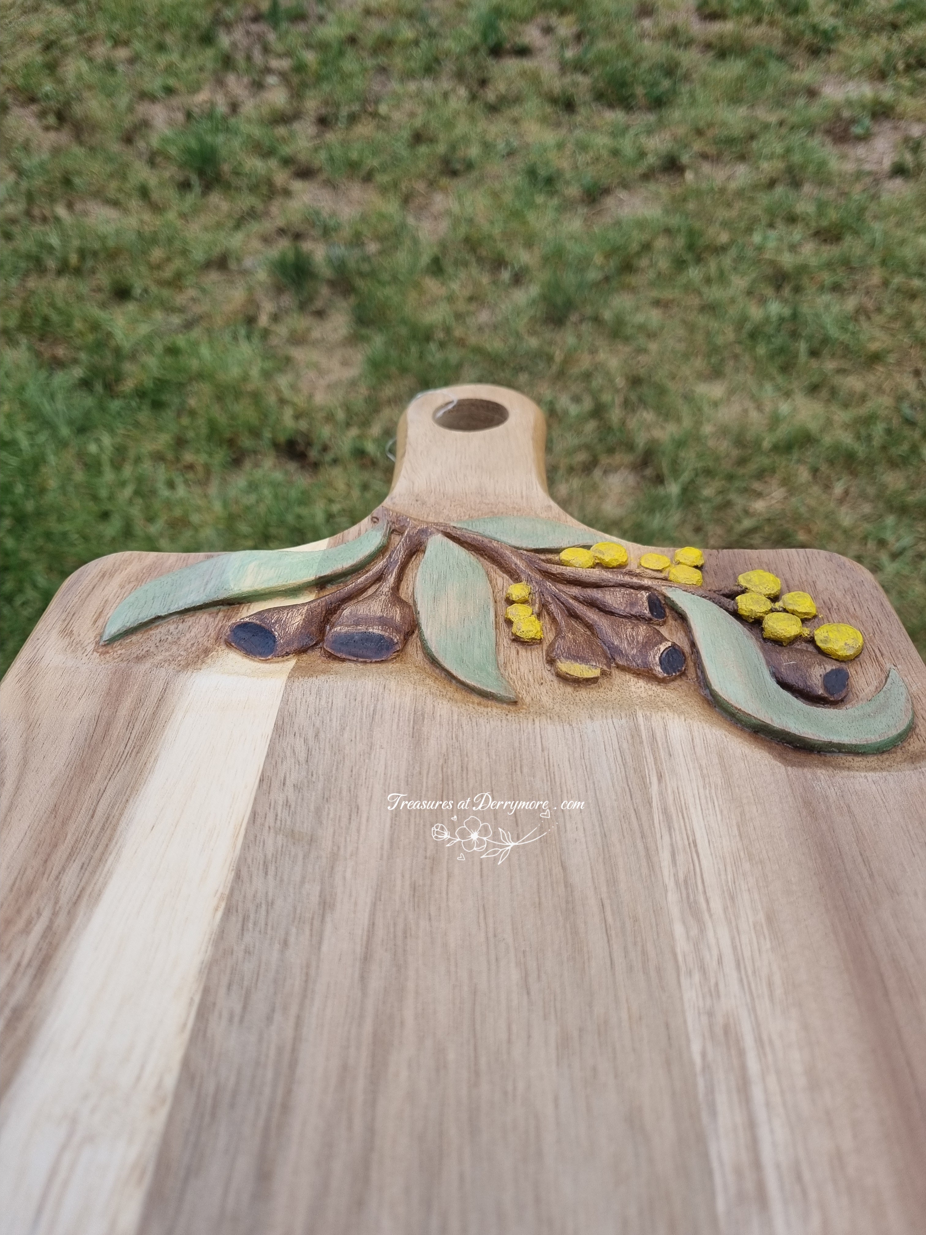 Chopping board with Australian themed design hand carved on upper part of board. Relief carving Wattle, Eucalyptus leaves, gum nuts
