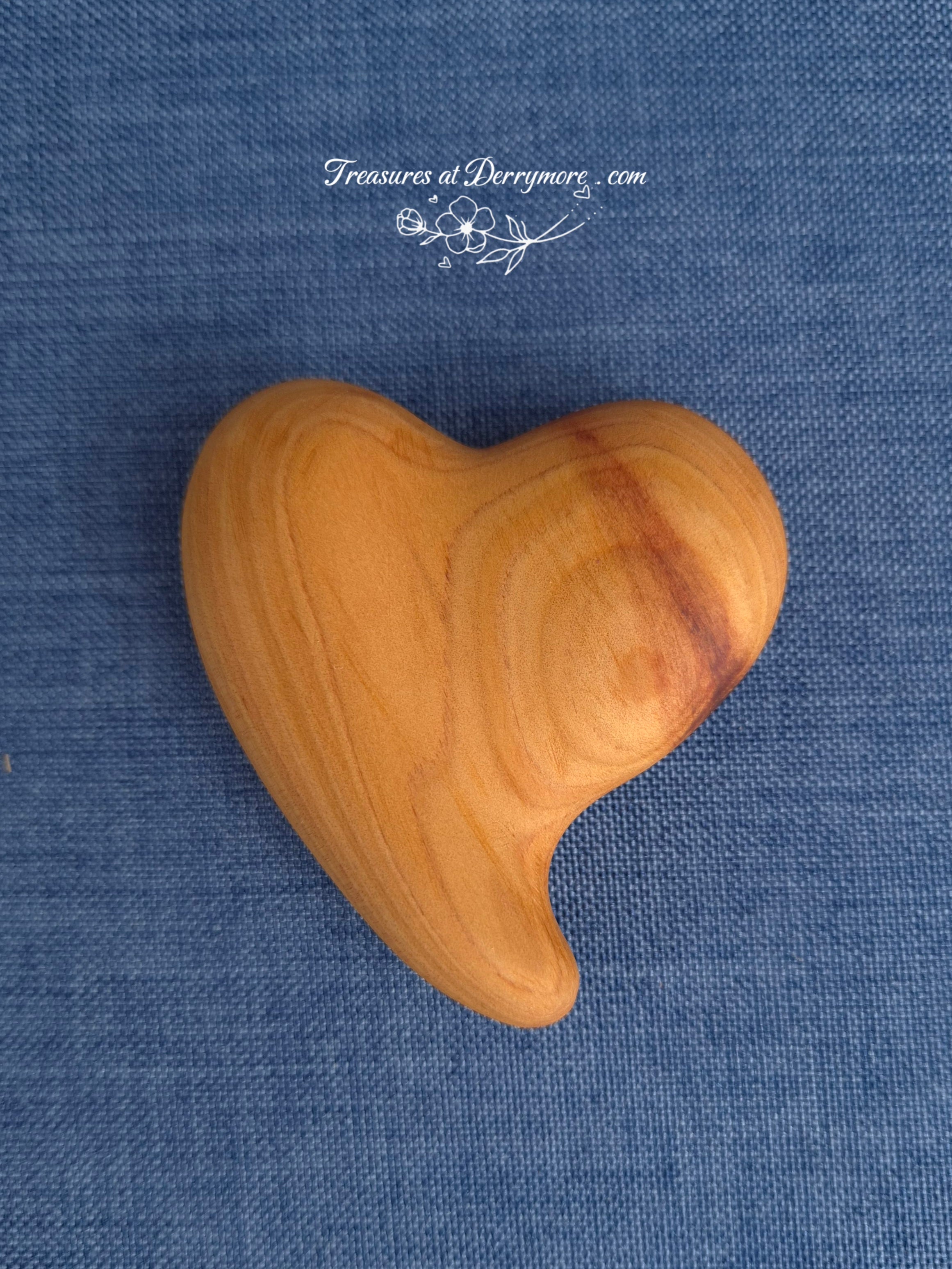 Carved Wooden comfort heart on a blue fabric background with 'Treasures at Derrymore' branding.