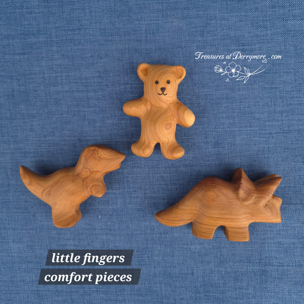 2 small carved wooden dinosaurs & 1 small carved wooden bear on a blue fabric background with 'Treasures at Derrymore' branding 