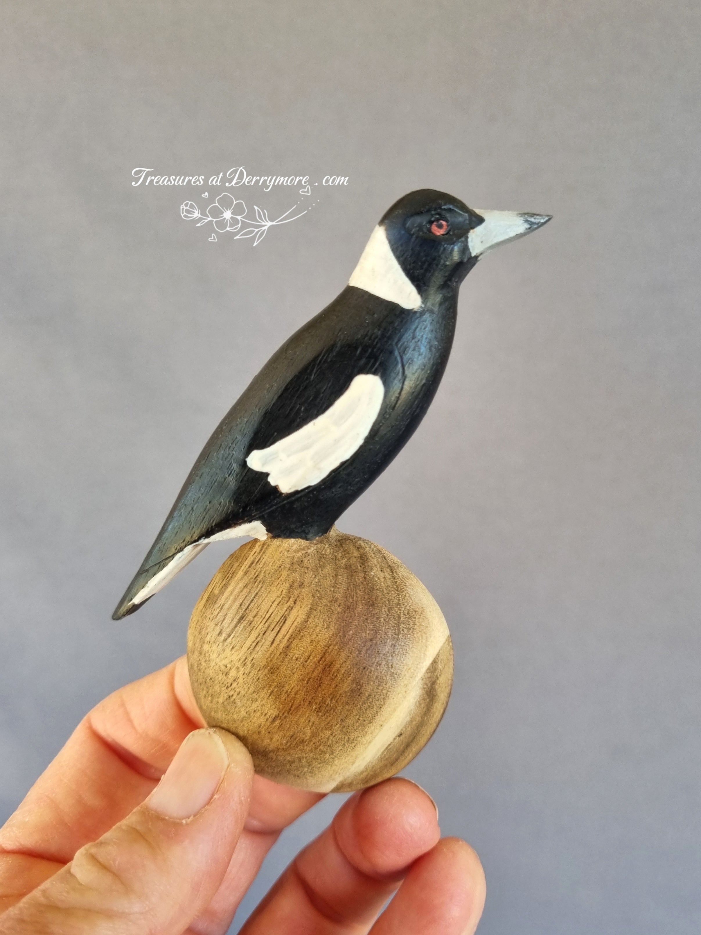 Hand carved wooden spoon with painted Australian magpie handle held in hand