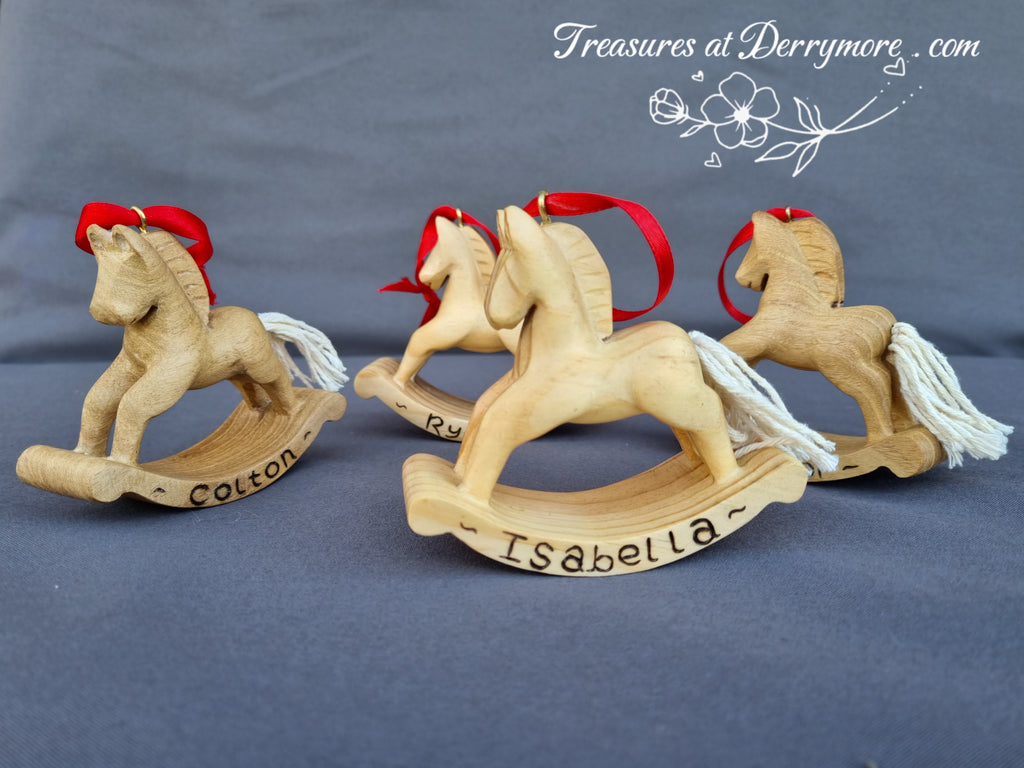 Three hand carved wooden rocking horses. Christmas decorations with red bows on a gray background, branded 'Treasures at Derrymore'.