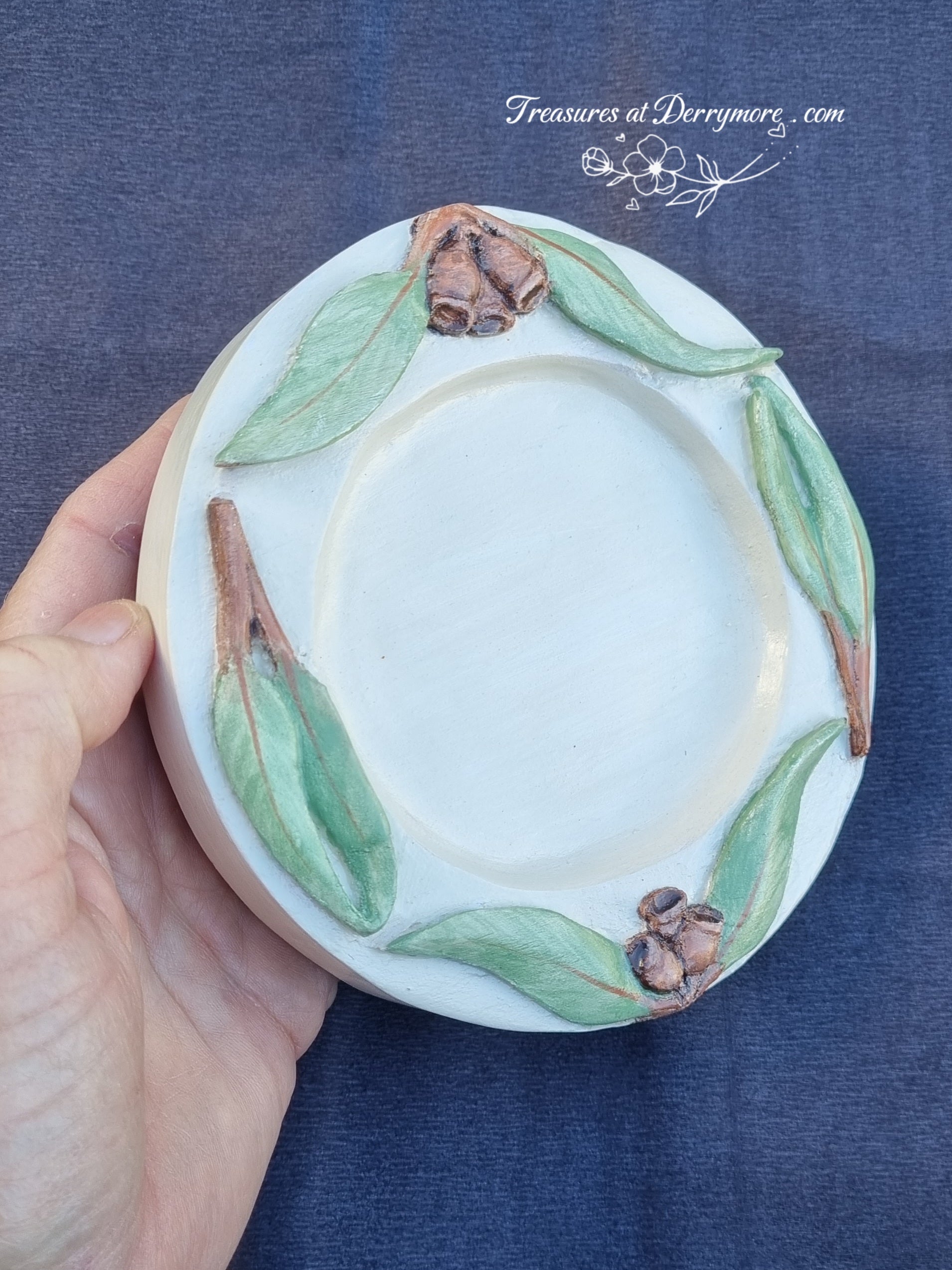 Hand carved round wooden dish with relief carved & green painted Eucalyptus leaves & brown gumnuts around the rim of dish 