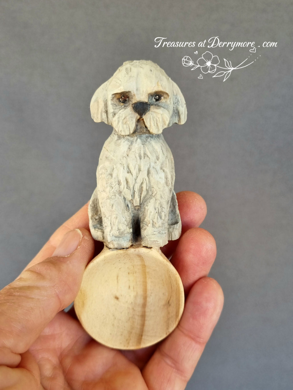 Hand carved wooden spoon with carved handle of painted small white dog held in hand