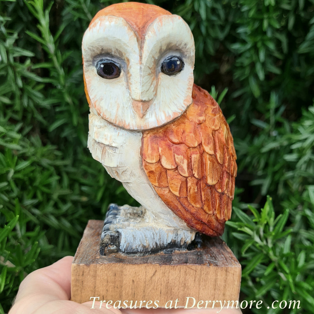 carved Wooden owl figurine held in front of green foliage
