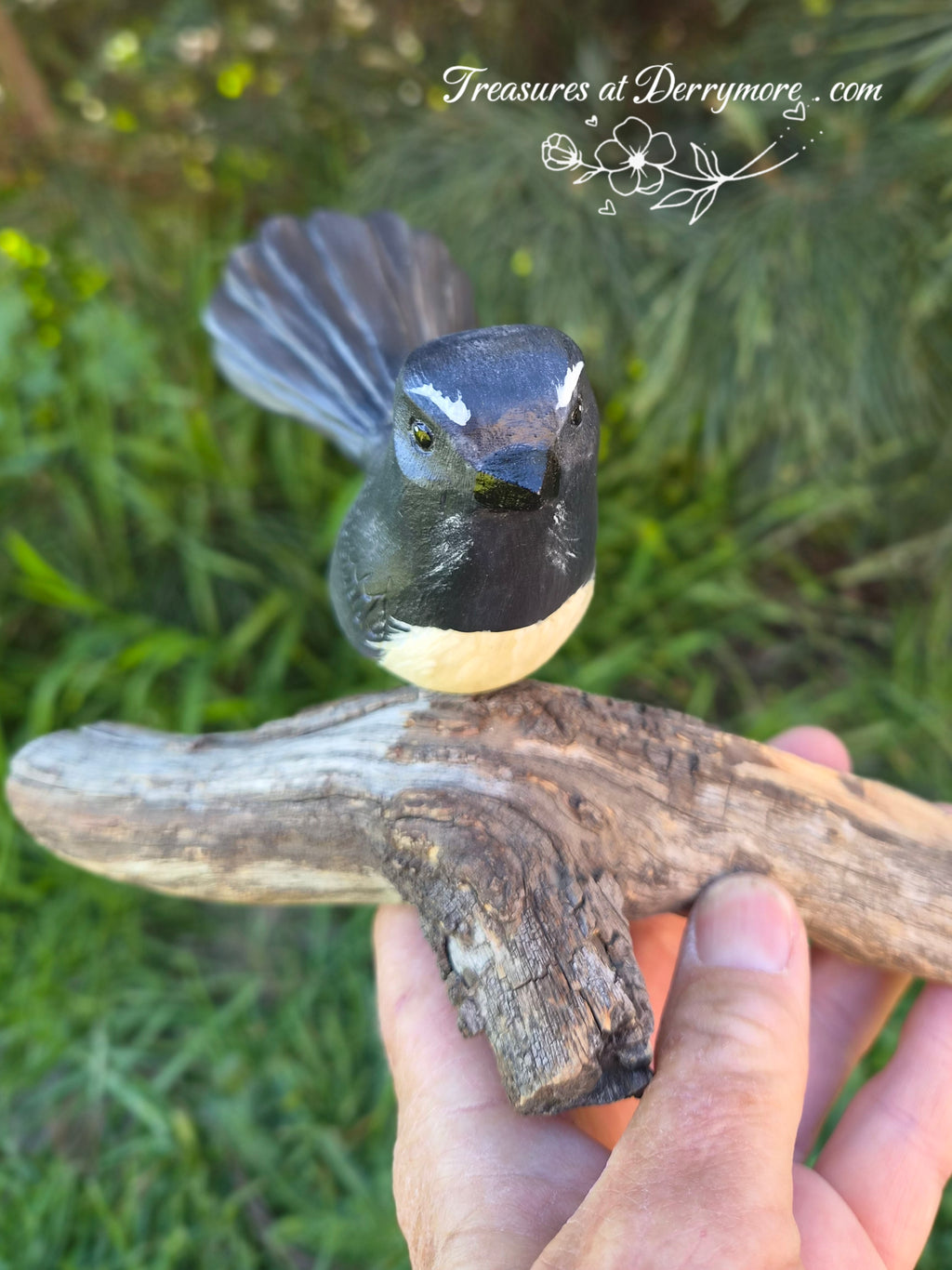 Hand carved Williewagtail sitting on natural bit of tree branch. Front view of carved wooden Williewagtail 