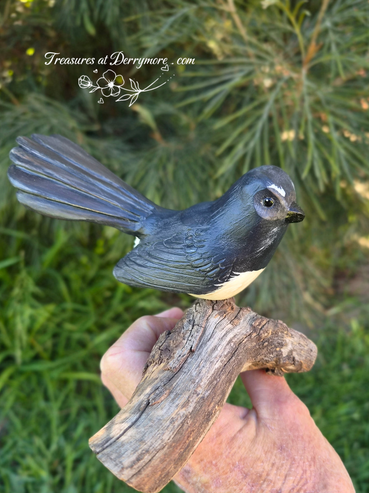 Hand carved Williewagtail sitting on natural bit of tree branch. Side view of carved wooden Williewagtail 